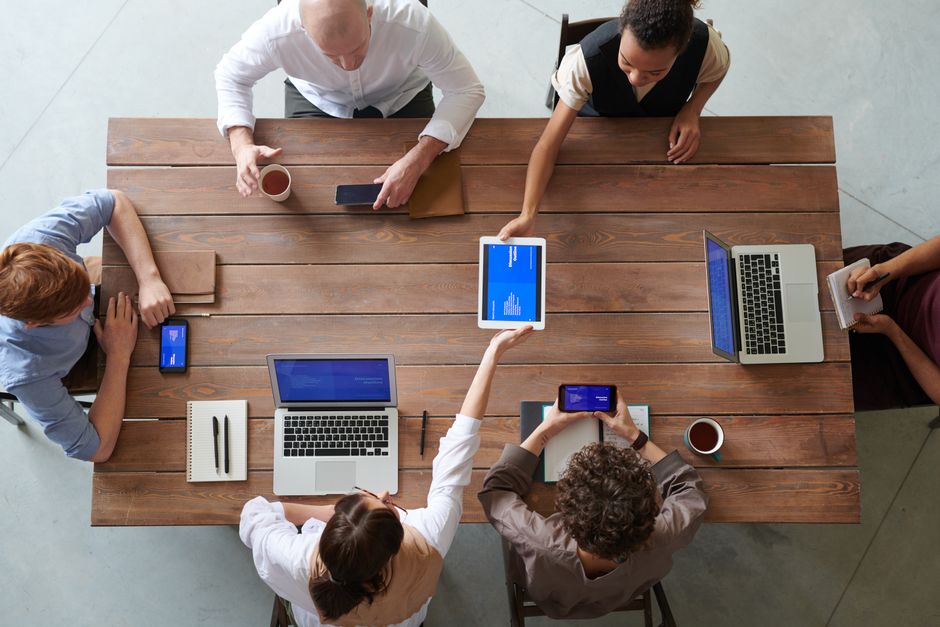 A diverse group of professionals engaged in a productive office meeting using digital devices.